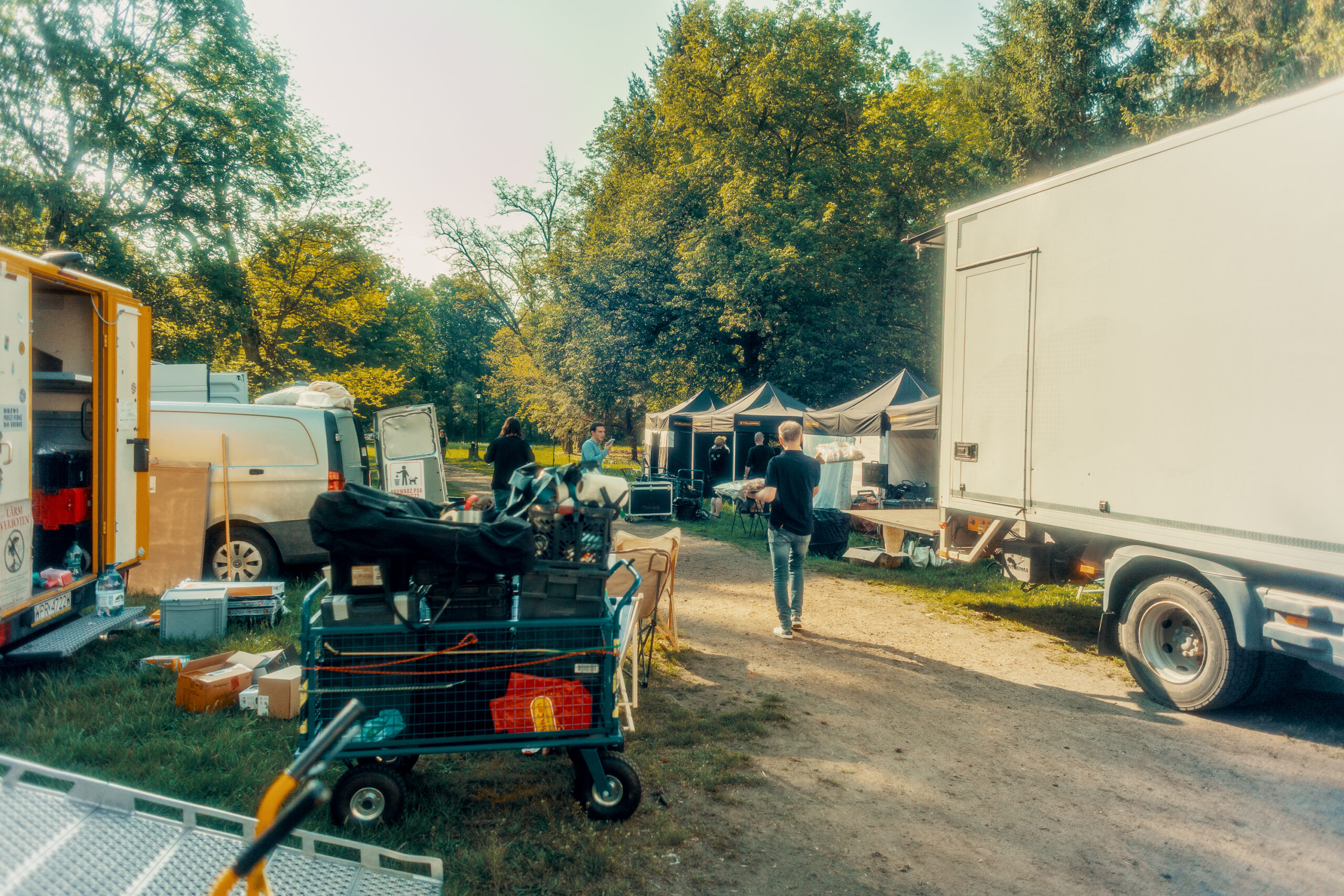 Baza produkcyjna na planie filmu reklamowego Chillberry – samochody ze sprzętem, wózki i namioty w parku