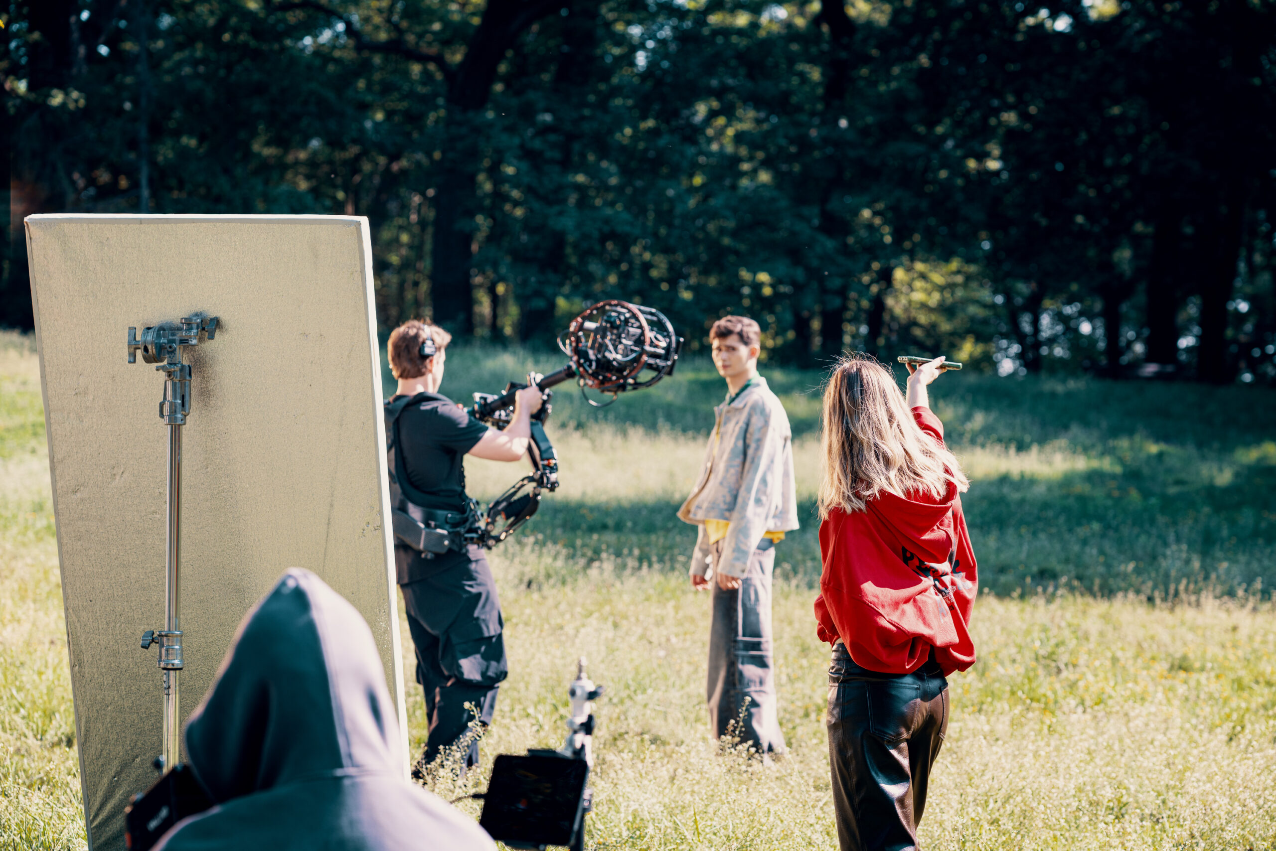 Operator ze stabilizowaną kamerą filmuje aktorów na planie filmu reklamowego Chillberry, obok blenda i ekipa